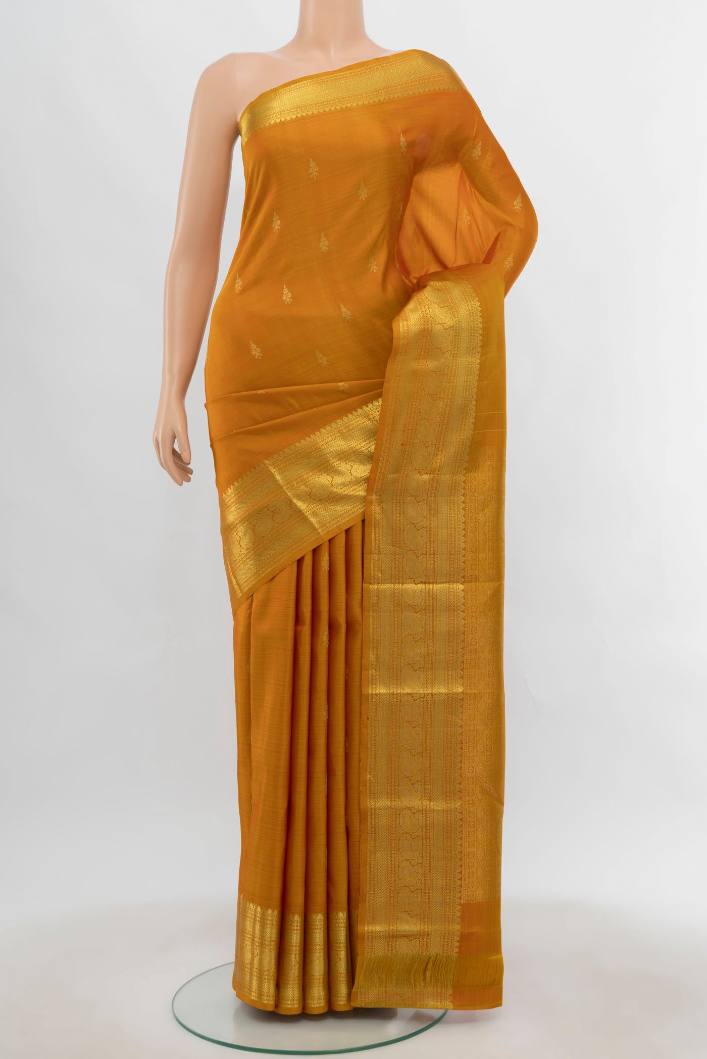 Mustard Kanchipuram Silk Saree with Zari Butta on the body and Silk Border.  displayed on a mannequin