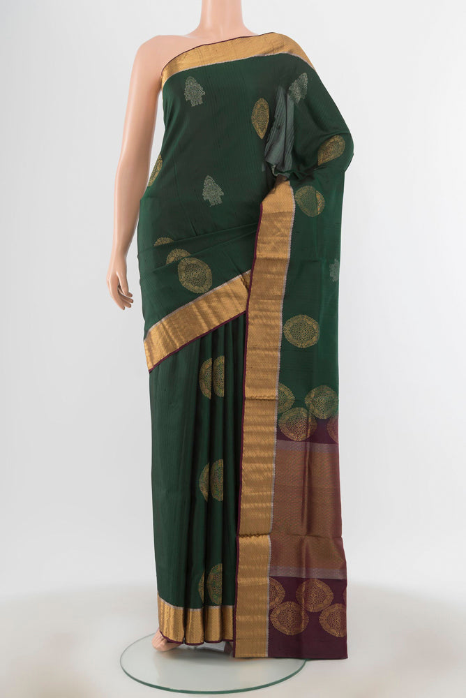 Bottle Green Soft Silk Saree with Zari Butta on the body and Silk Border.  displayed on a mannequin