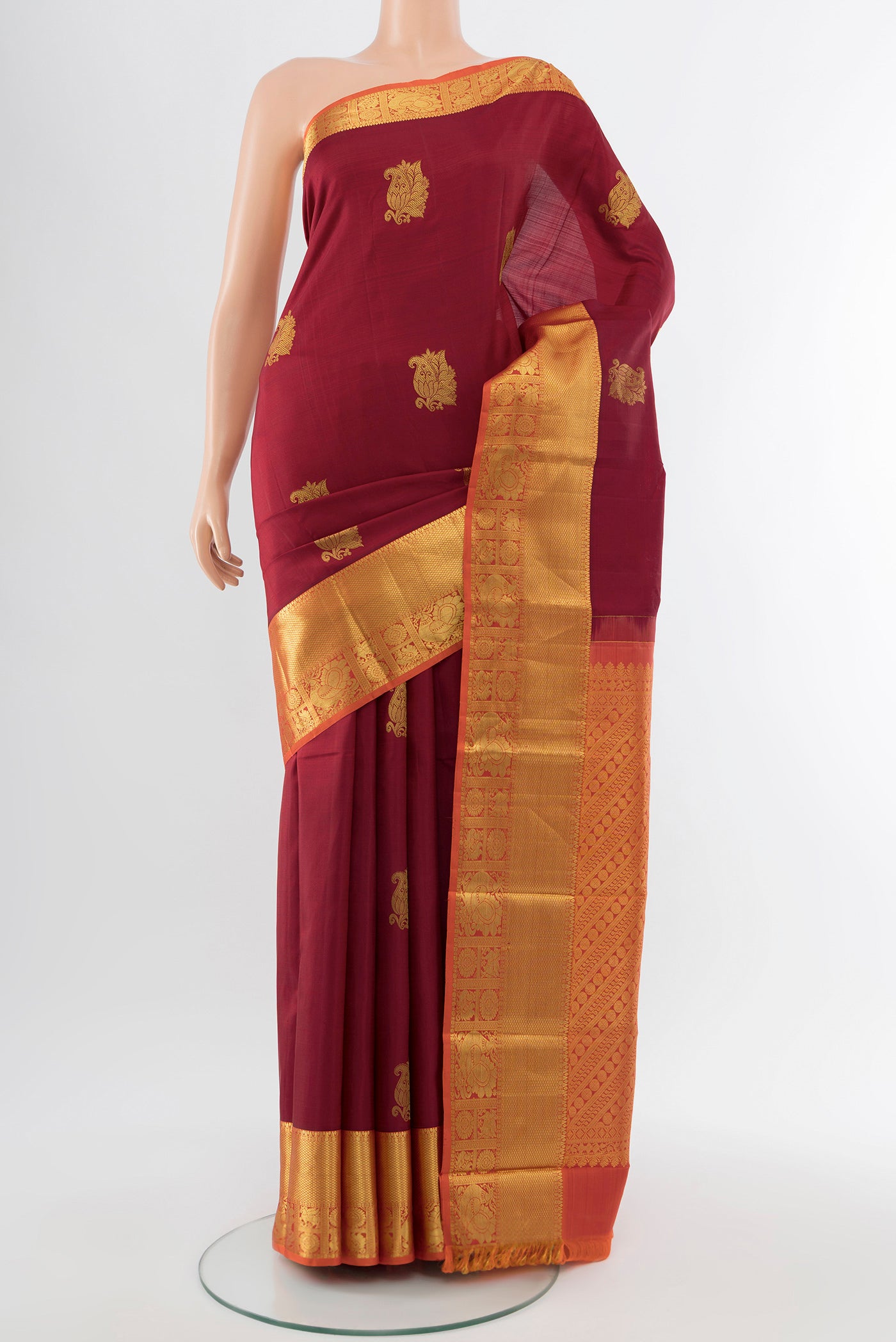 Maroon Kanchipuram Silk Saree with Zari Butta on the body and Silk Border.  displayed on a mannequin