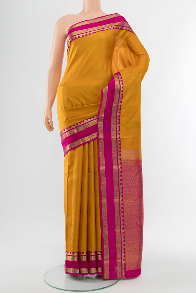 Mustard Kanchipuram Silk Saree with Zari Butta on the body and Silk Border.  displayed on a mannequin