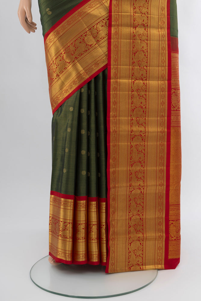 Pleats and pallu of Bottle Green Kanjivaram Silk Saree with Zari Butta on the body and Silk Border. 