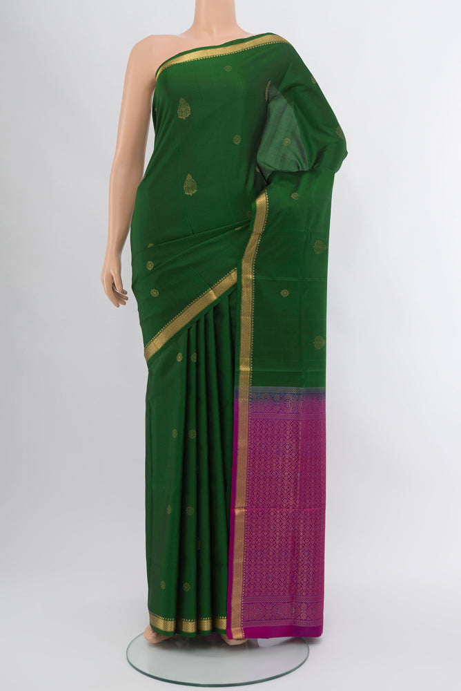 Bottle Green Soft Silk Saree with Zari Butta on the body and Silk Border.  displayed on a mannequin