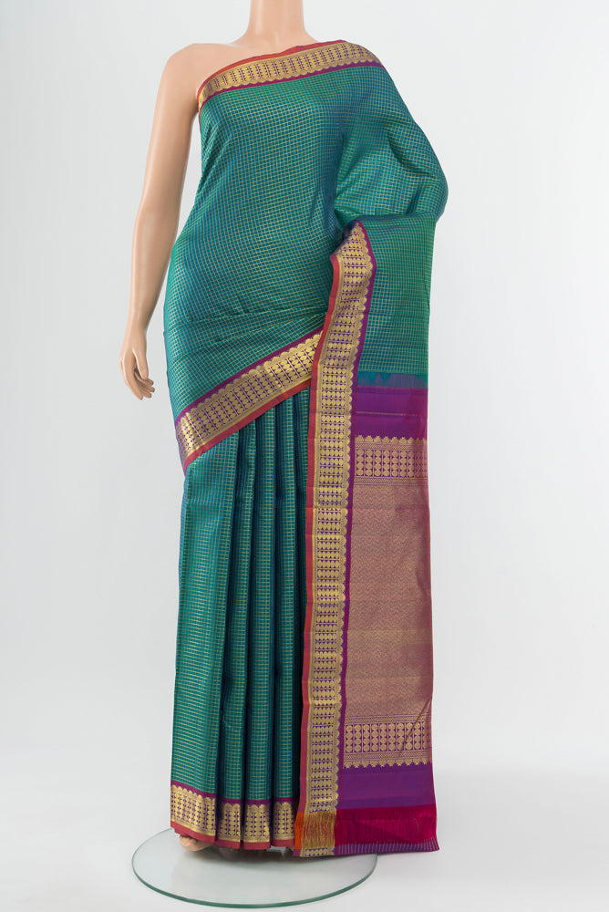 Peacock Blue Kanjivaram Silk Saree with Zari Butta on the body and Silk Border.  displayed on a mannequin