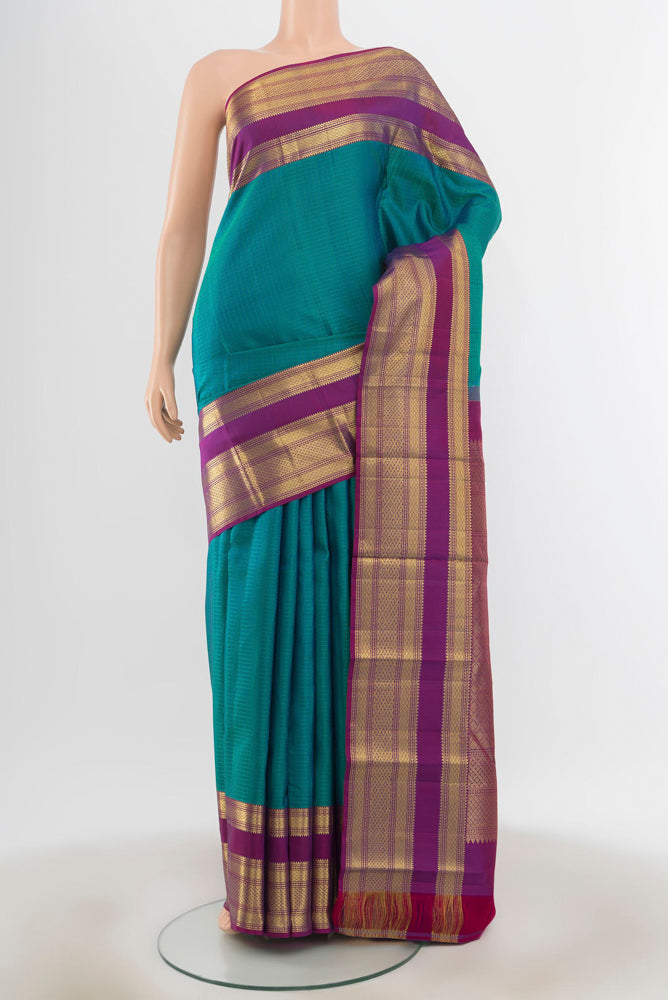 Peacock Blue Kanjivaram Silk Saree with Zari Butta on the body and Silk Border.  displayed on a mannequin