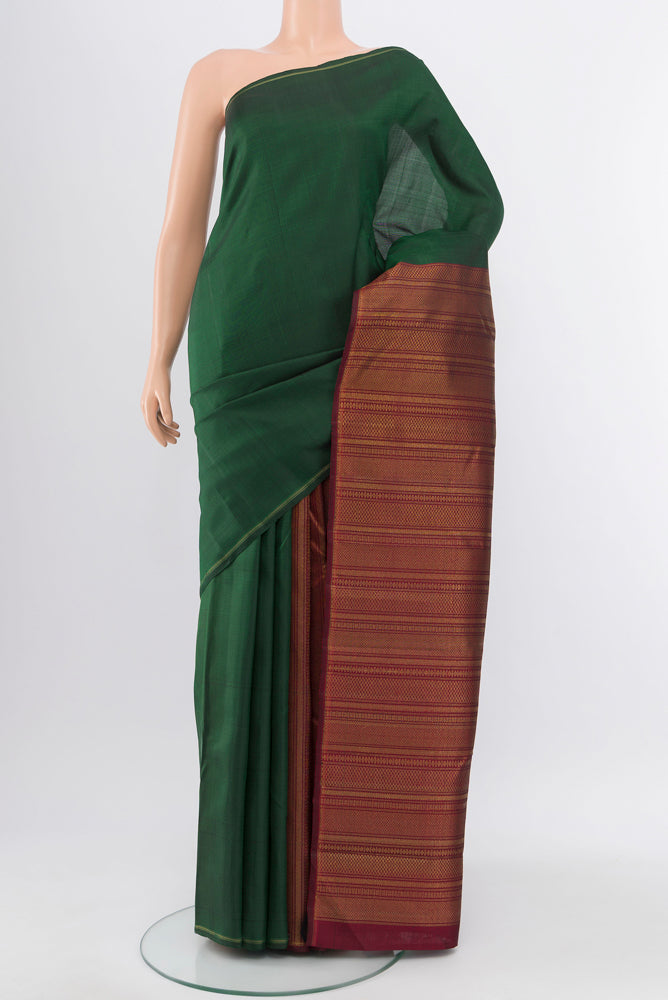 Pure Silk Pure Zari Bottle Green Kanjivaram Saree with Zari Butta on the body and Silk Border.  displayed on a mannequin