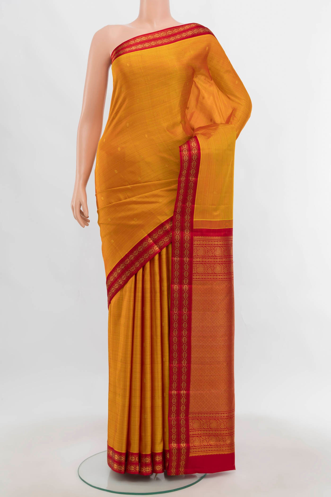 Mustard Kanchipuram Silk Saree with Zari Butta on the body and Zari Border.  displayed on a mannequin