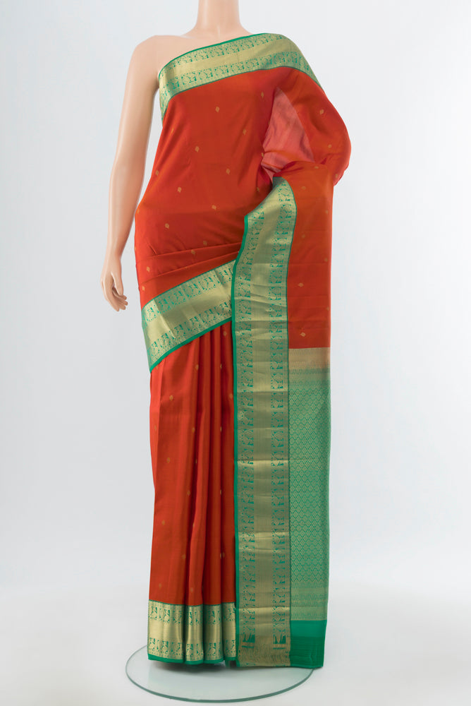 Rust Kanchipuram Silk Saree with Zari Butta on the body and Silk Border.  displayed on a mannequin
