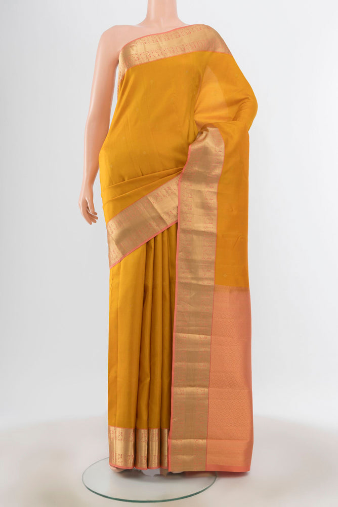 Mustard Kanchipuram Silk Saree with Zari Butta on the body and Silk Border.  displayed on a mannequin