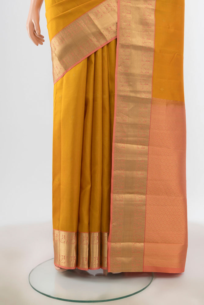 Pleats and pallu of Mustard Kanchipuram Silk Saree with Zari Butta on the body and Silk Border. 