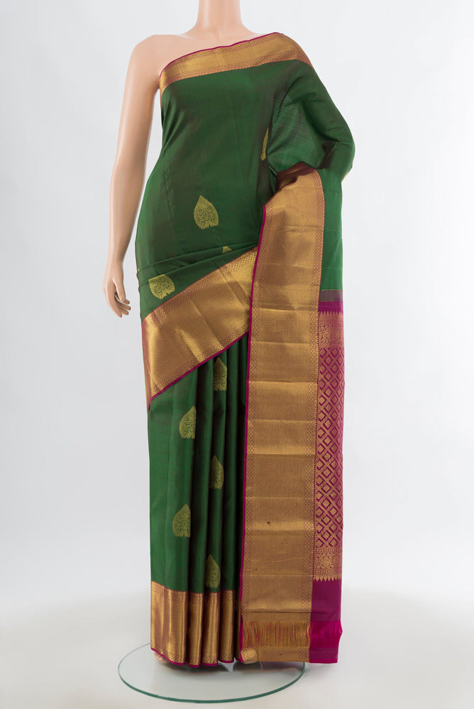 Bottle Green Kanchipuram Silk Saree with Zari Butta on the body and Silk Border.  displayed on a mannequin