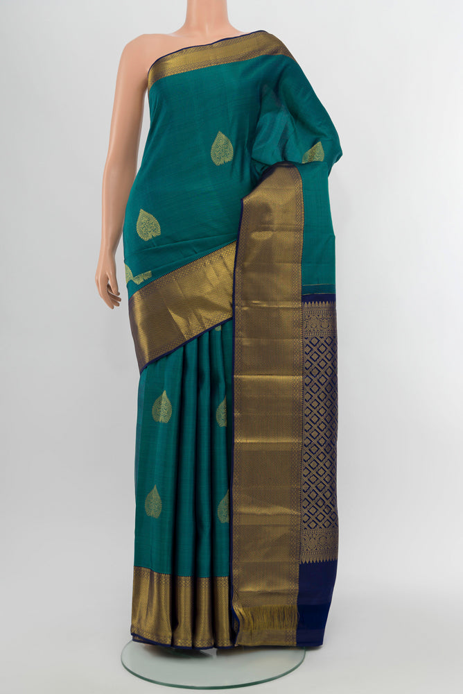 Peacock Blue Kanchipuram Silk Saree with Zari Butta on the body and Silk Border.  displayed on a mannequin