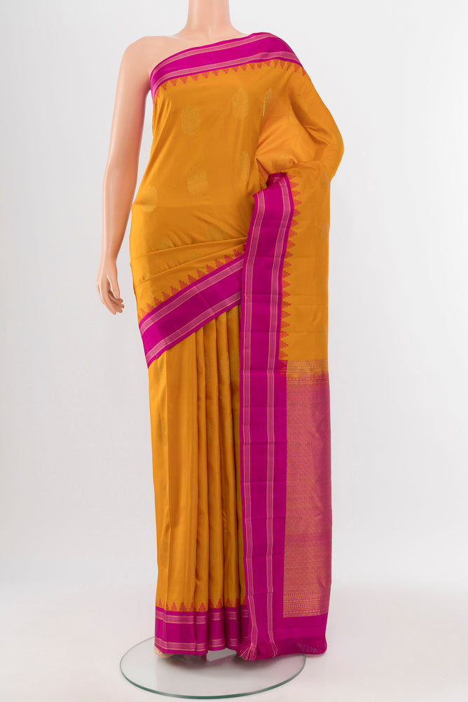 Mustard Kanchipuram Silk Saree with Zari Butta on the body and Silk Border.  displayed on a mannequin