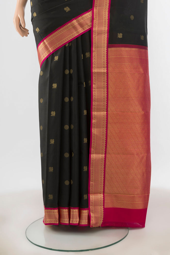 Pleats and pallu of Black Kanchipuram Silk Saree with Zari Butta on the body and Silk Border. 