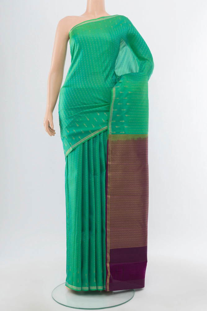 Light Green Kanchipuram Silk Saree with Zari Butta on the body and Silk Border.  displayed on a mannequin