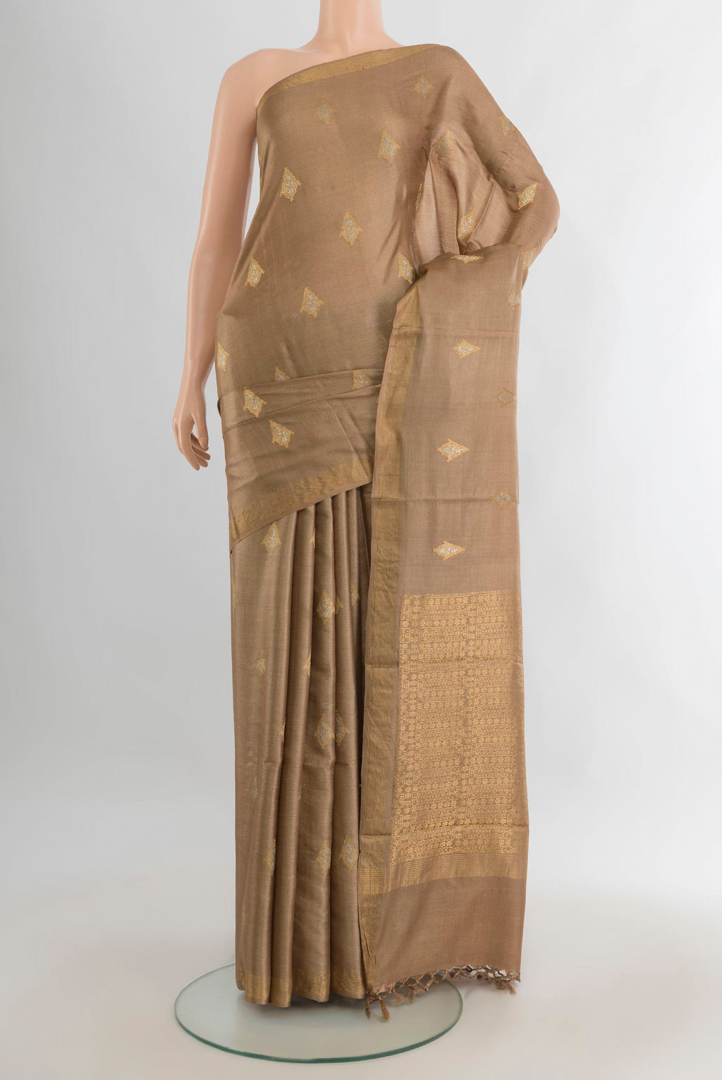 Beige Tussar Saree with Zari Butta on the body and Zari Border.  displayed on a mannequin