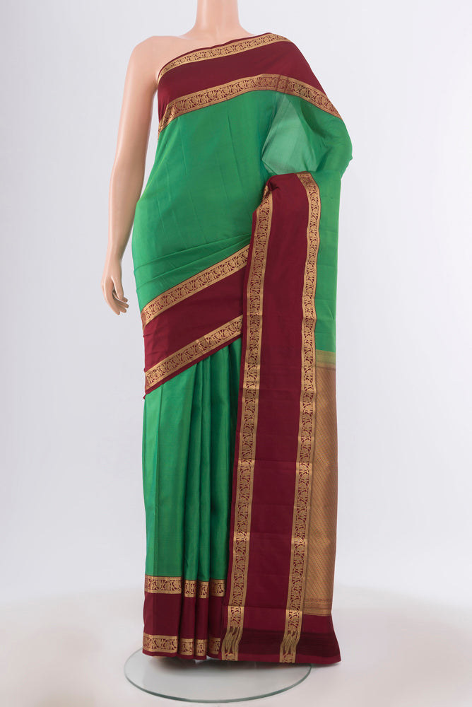 Light Green Kanchipuram Silk Saree with Zari Butta on the body and Silk Border.  displayed on a mannequin