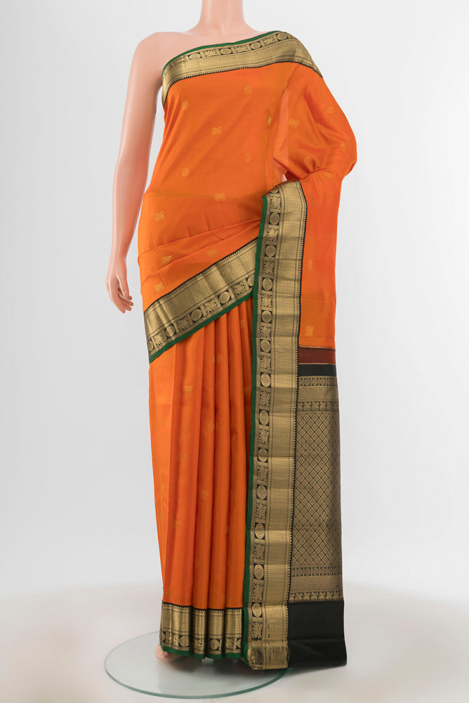 Brick Orange Kanchipuram Silk Saree with Zari Butta on the body and Silk Border.  displayed on a mannequin