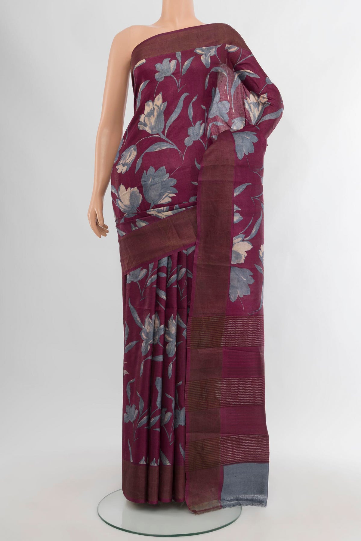 Burgundy Tussar Silk Saree with Floral Print on the body and Zari Border.  displayed on a mannequin