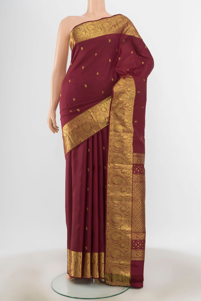 Maroon Kanchipuram Silk Saree with Zari Butta on the body and Silk Border.  displayed on a mannequin