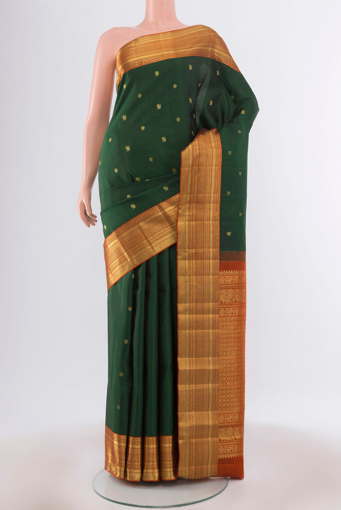 Bottle Green Kanchipuram Silk Saree with Zari Butta on the body and Silk Border.  displayed on a mannequin