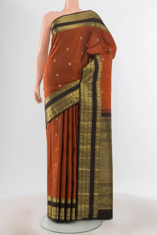 Pure Silk Pure Zari Rust Kanjivaram Saree with Zari Butta on the body and Silk Border.  displayed on a mannequin