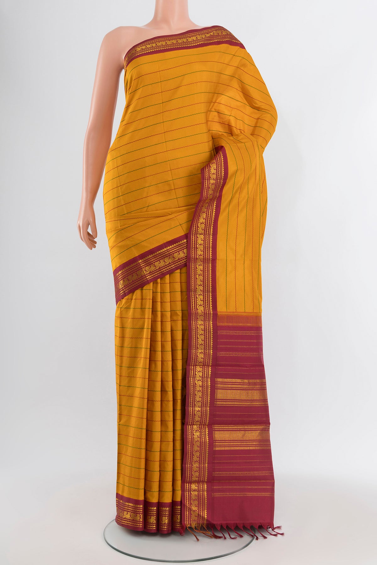 Mustard Kanjivaram Silk Saree with Veldhari on the body and Zari Border.  displayed on a mannequin