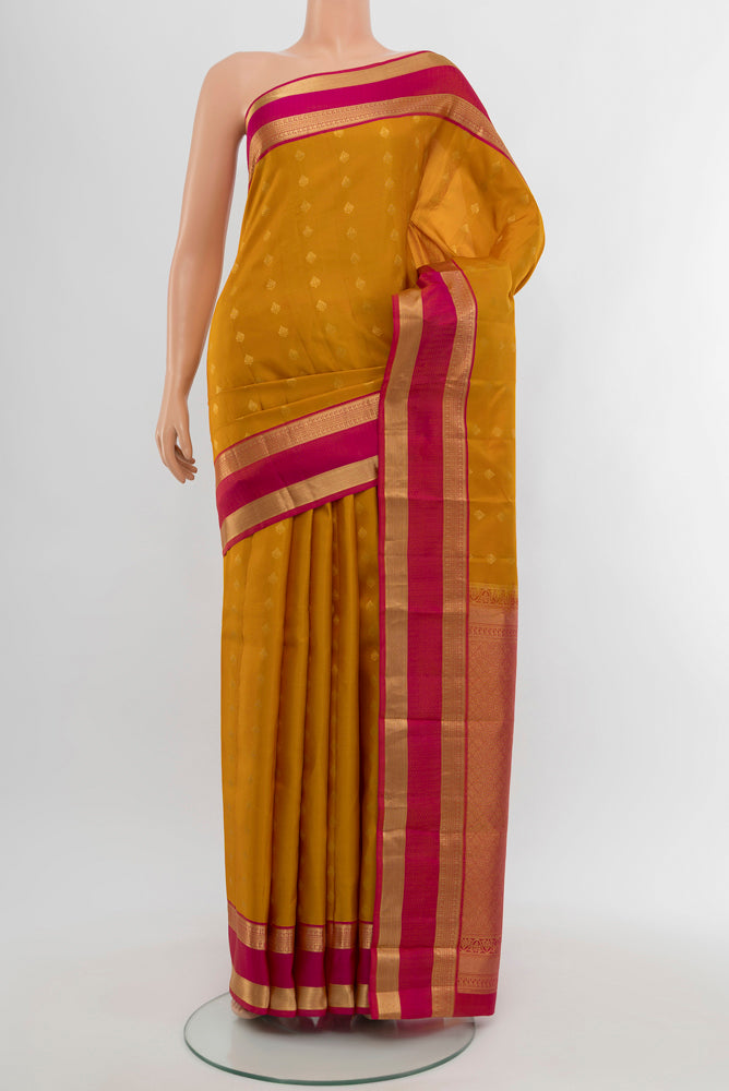 Mustard Kanchipuram Silk Saree with Zari Butta on the body and Silk Border.  displayed on a mannequin