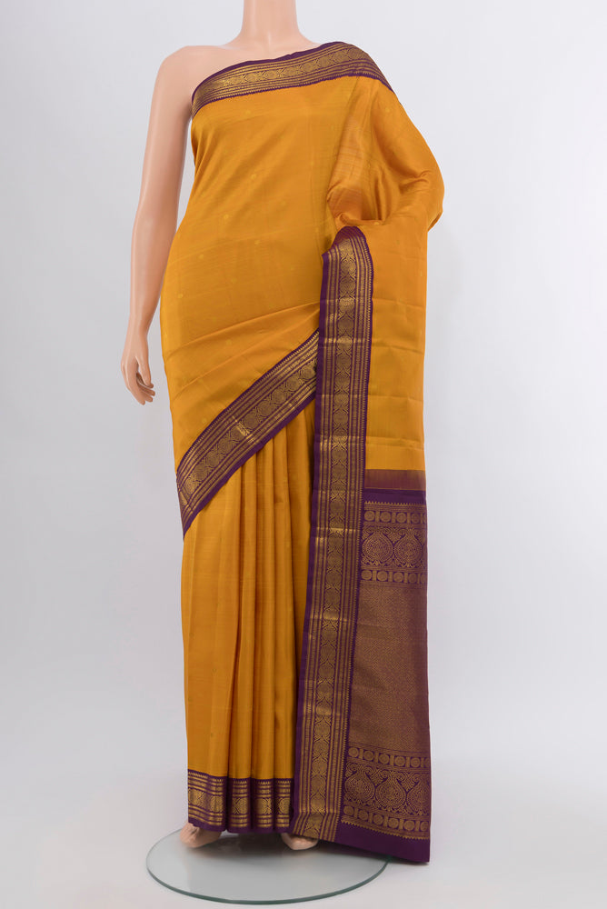 Mustard Kanjivaram Silk Saree with Zari Butta on the body and Silk Border.  displayed on a mannequin