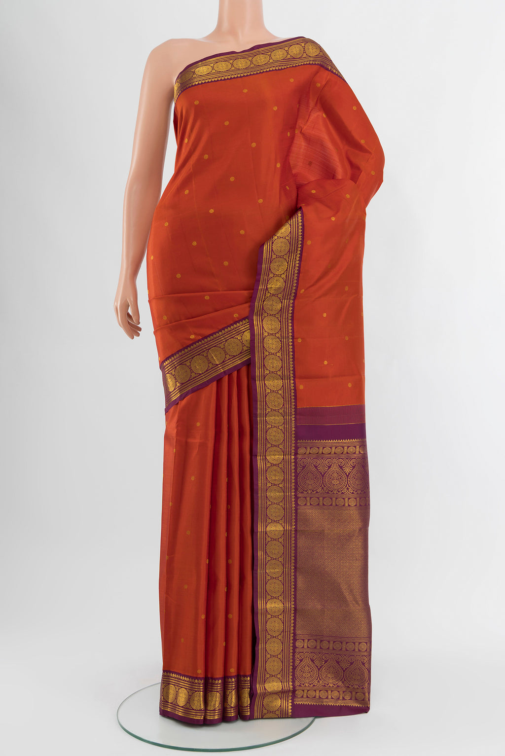 Rust Kanjivaram Silk Saree with Zari Butta on the body and Zari Border.  displayed on a mannequin