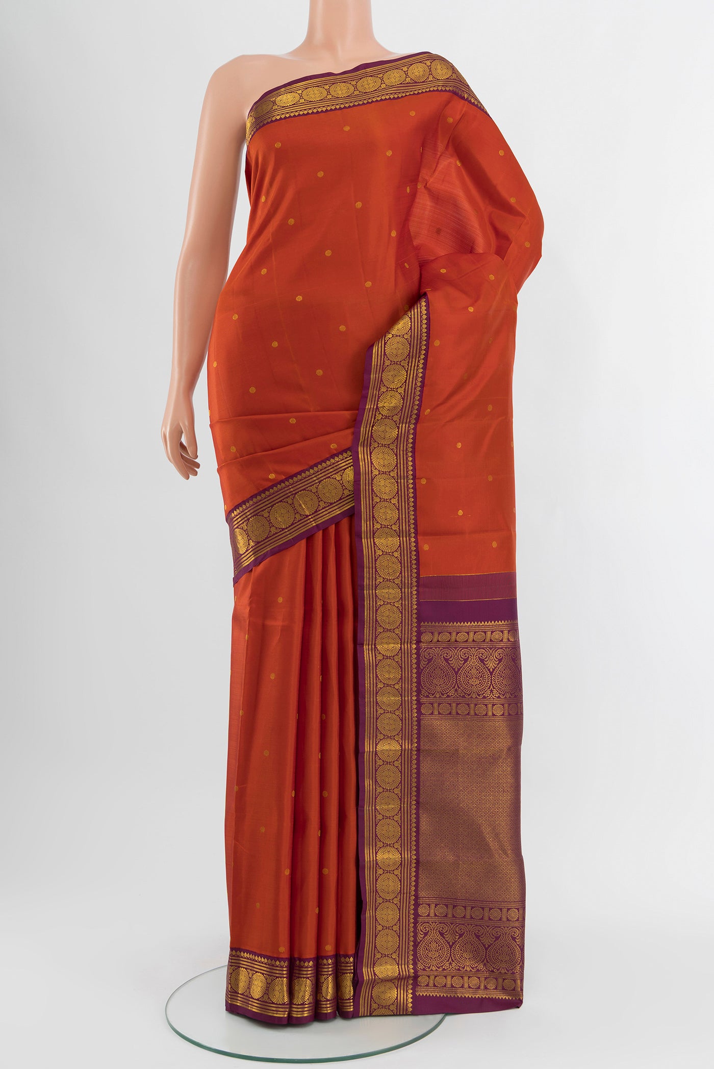Rust Kanjivaram Silk Saree with Zari Butta on the body and Zari Border.  displayed on a mannequin