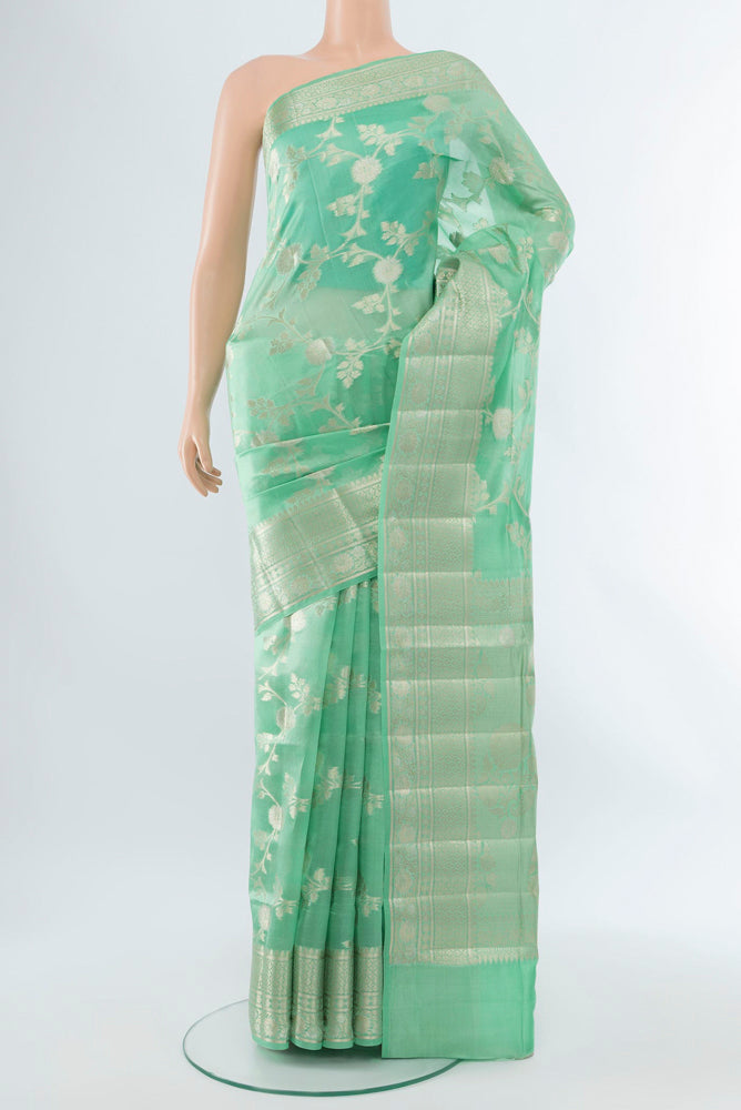 Light Green Banarasi Raw Silk Saree with Zari Butta on the body and Silk Border.  displayed on a mannequin