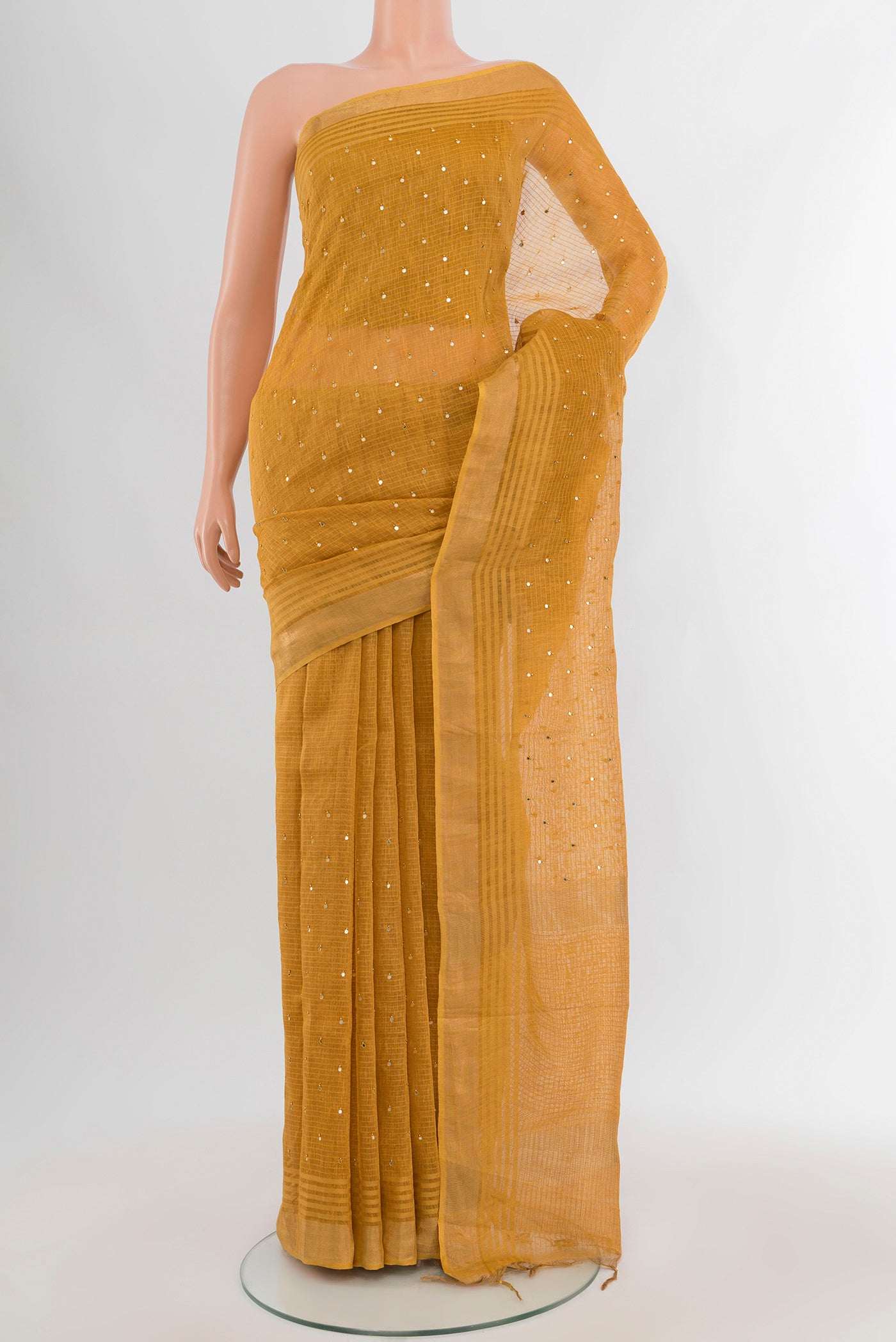 Mustard Tussar Silk Saree with Embroidery on the body and Zari Border.  displayed on a mannequin