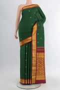 Bottle Green Kanchipuram Silk Saree with Zari Butta on the body and Zari Border.  displayed on a mannequin