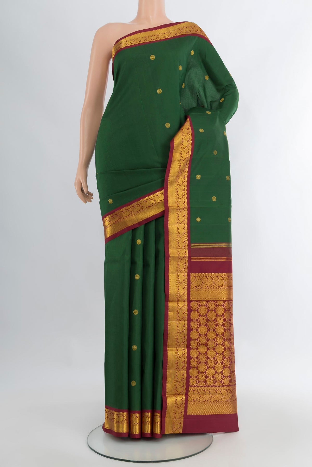 Bottle Green Kanchipuram Silk Saree with Zari Butta on the body and Zari Border.  displayed on a mannequin
