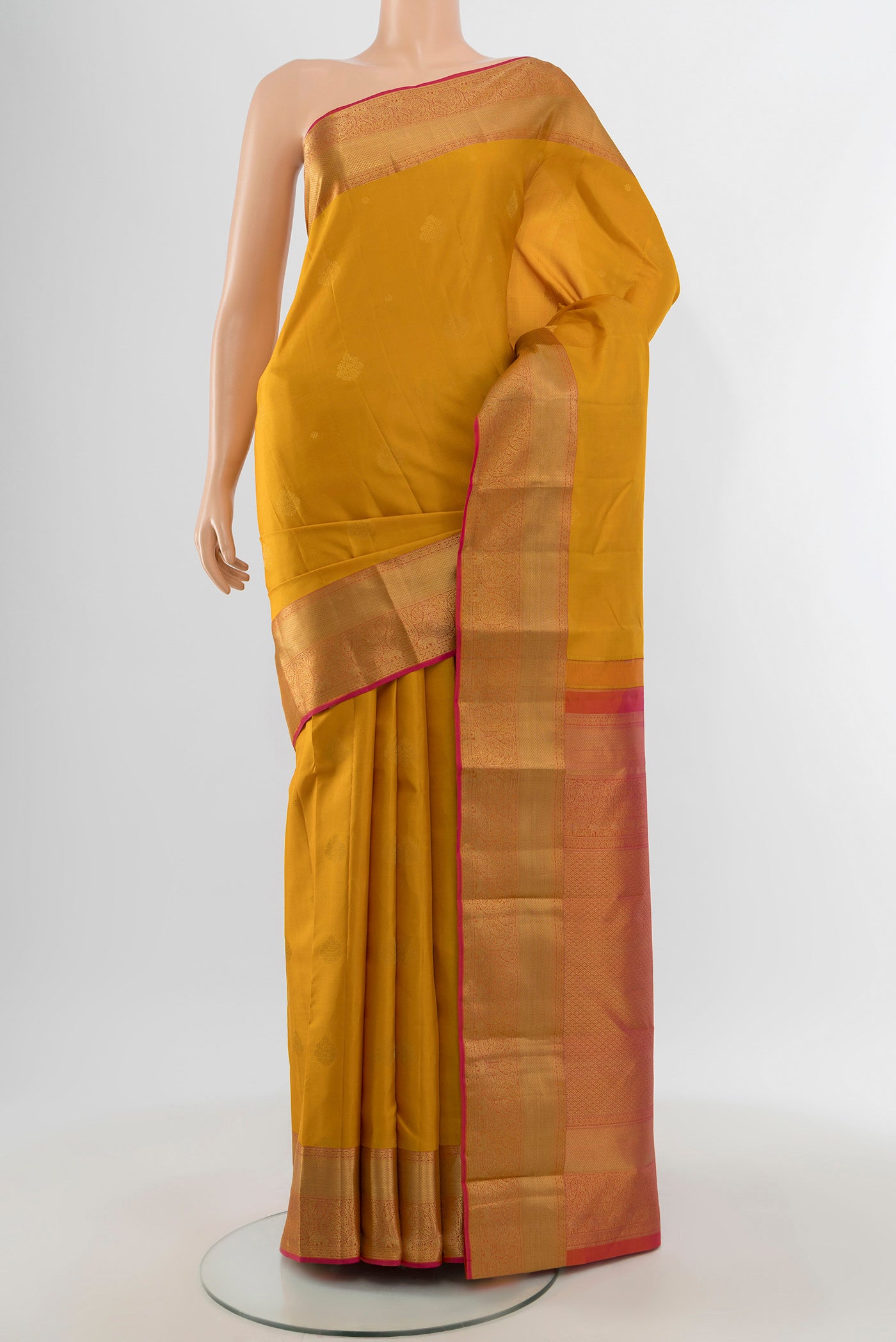 Mustard Kanjivaram Silk Saree with Zari Butta on the body and Zari Border.  displayed on a mannequin