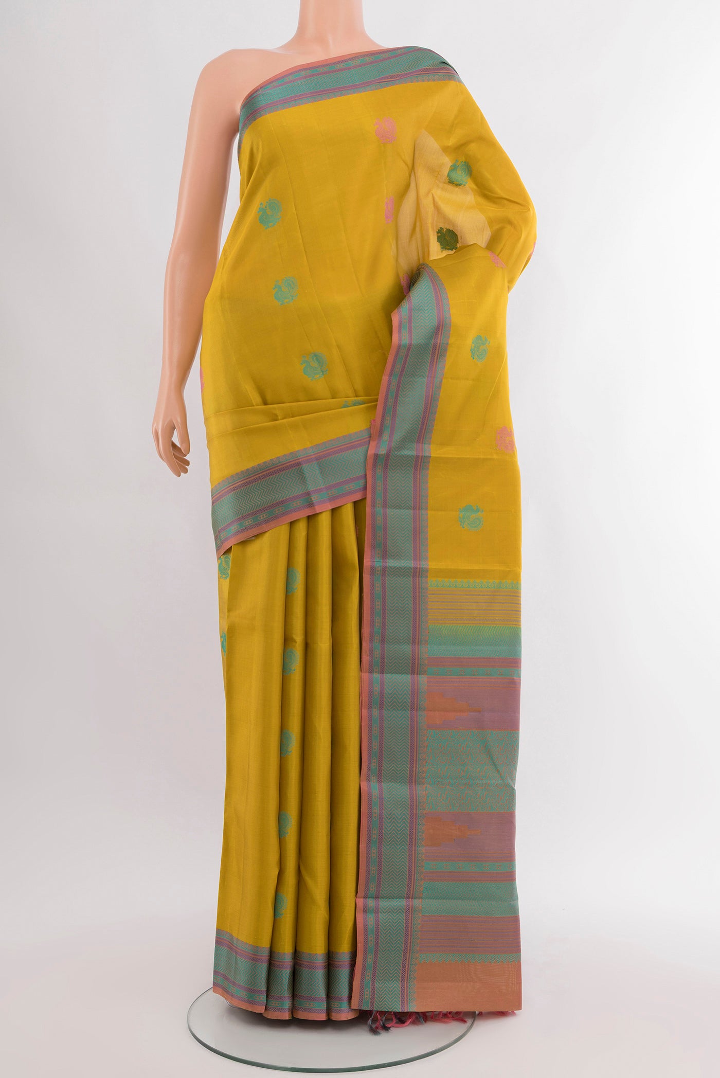 Mustard Kanchipuram Silk Saree with Zari Butta on the body and Silk Border.  displayed on a mannequin