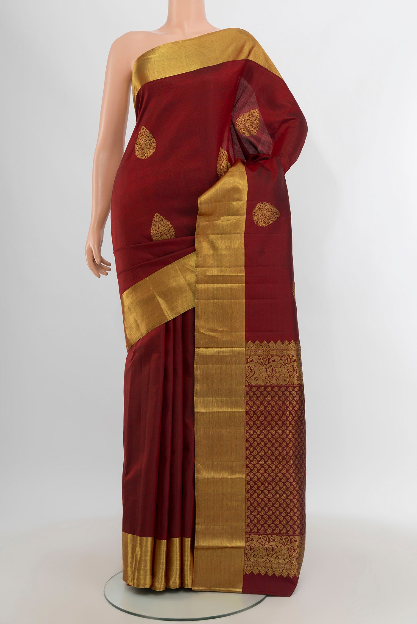 Maroon Kanchipuram Silk Saree with Zari Butta on the body and Zari Border.  displayed on a mannequin