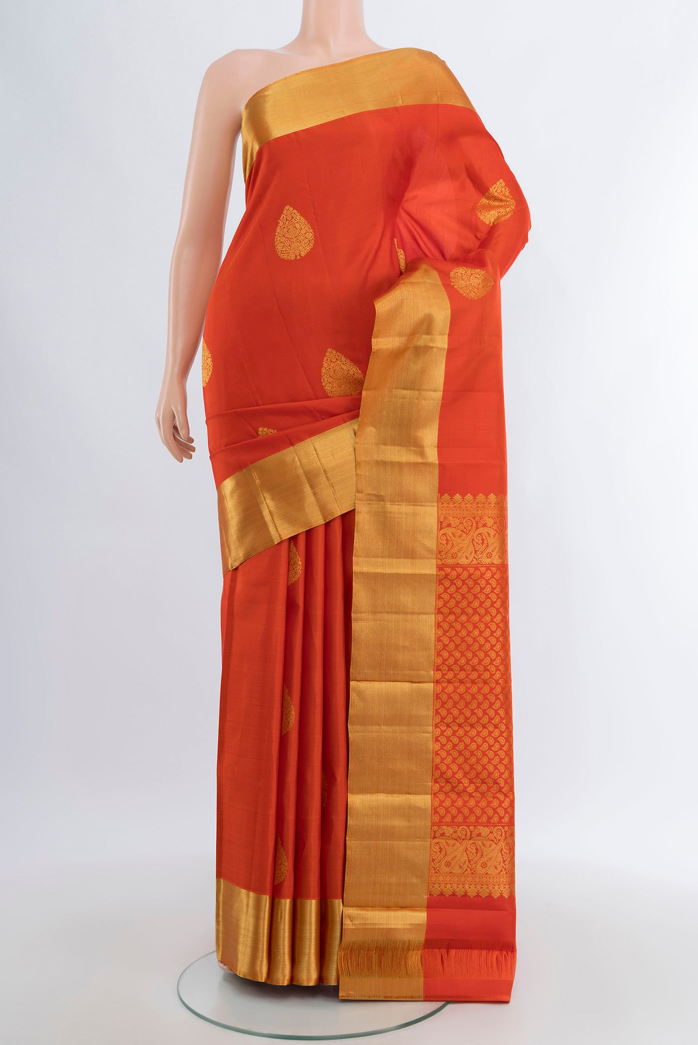 Orange Kanchipuram Silk Saree with Zari Butta on the body and Zari Border.  displayed on a mannequin