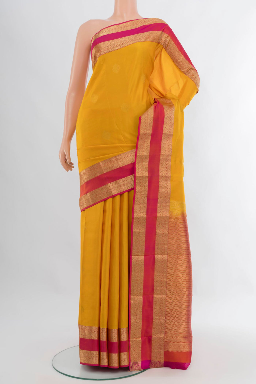 Mustard Kanchipuram Silk Saree with Zari Butta on the body and Zari Border.  displayed on a mannequin