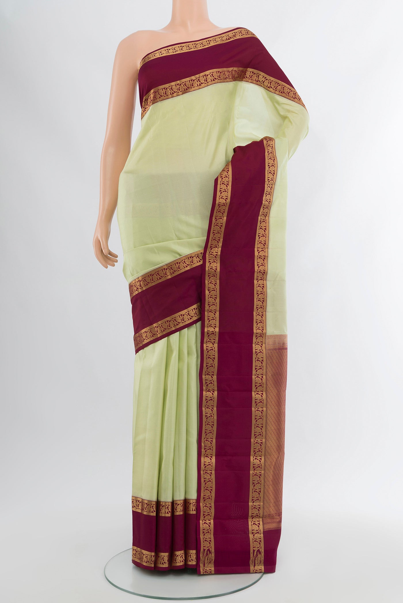 Pista Green Kanchipuram Silk Saree with Plain Body and Zari Border.  displayed on a mannequin