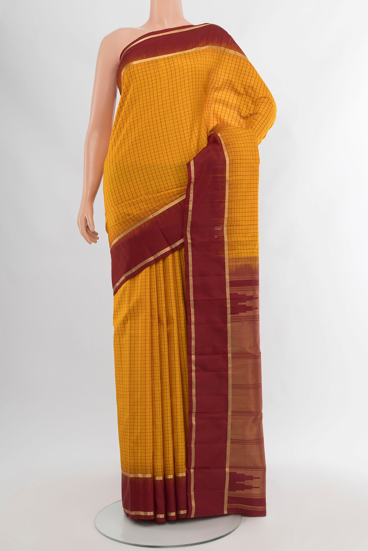 Mustard Kanchipuram Silk Saree with Checked design on the body and Plain Border.  displayed on a mannequin