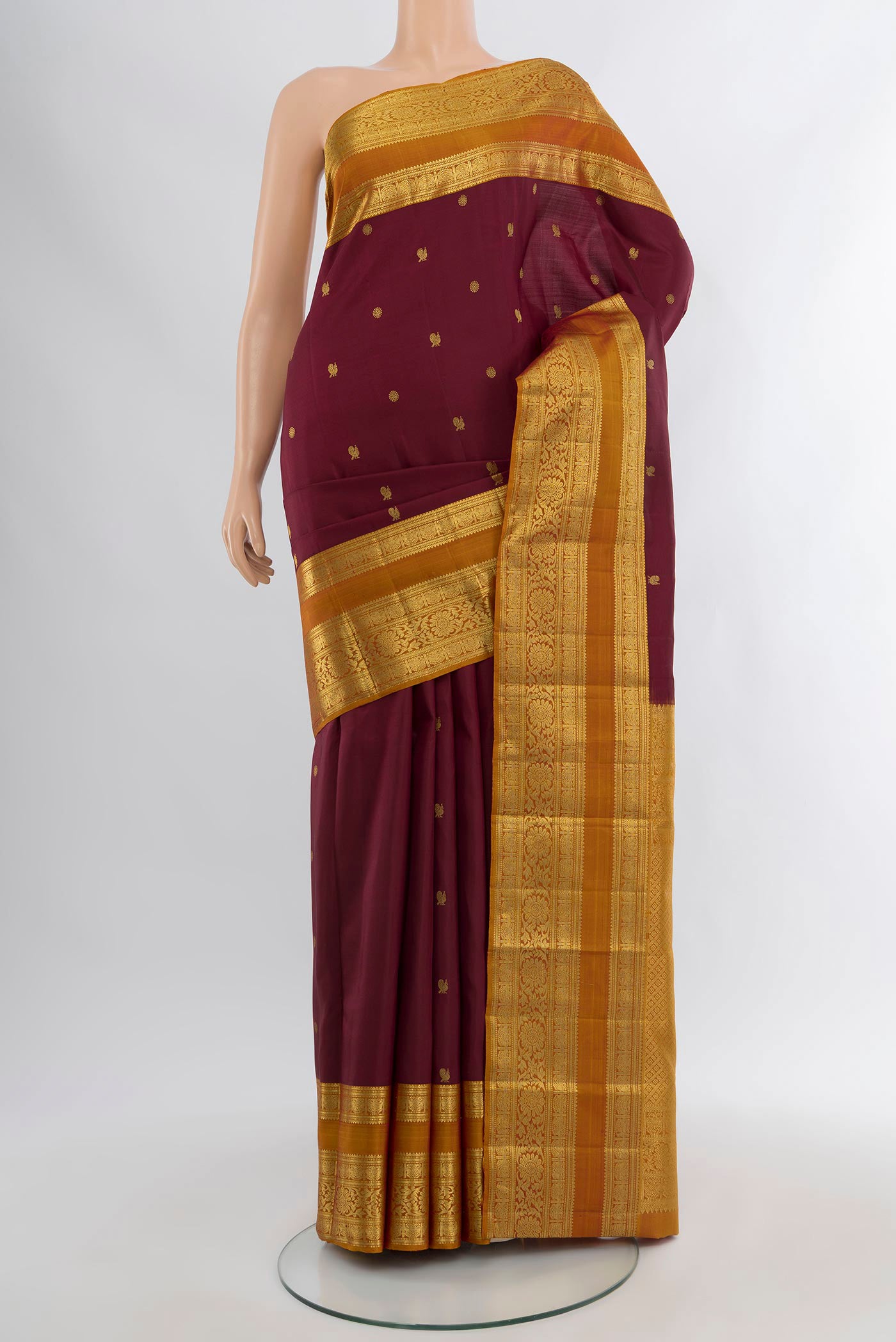 Maroon Kanchipuram Silk Saree with Zari Butta on the body and Zari Border.  displayed on a mannequin