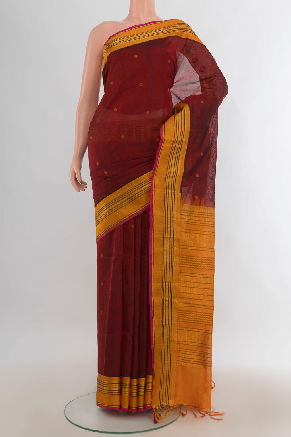 Maroon Silk Cotton Saree with Zari Butta on the body and Silk Border.  displayed on a mannequin