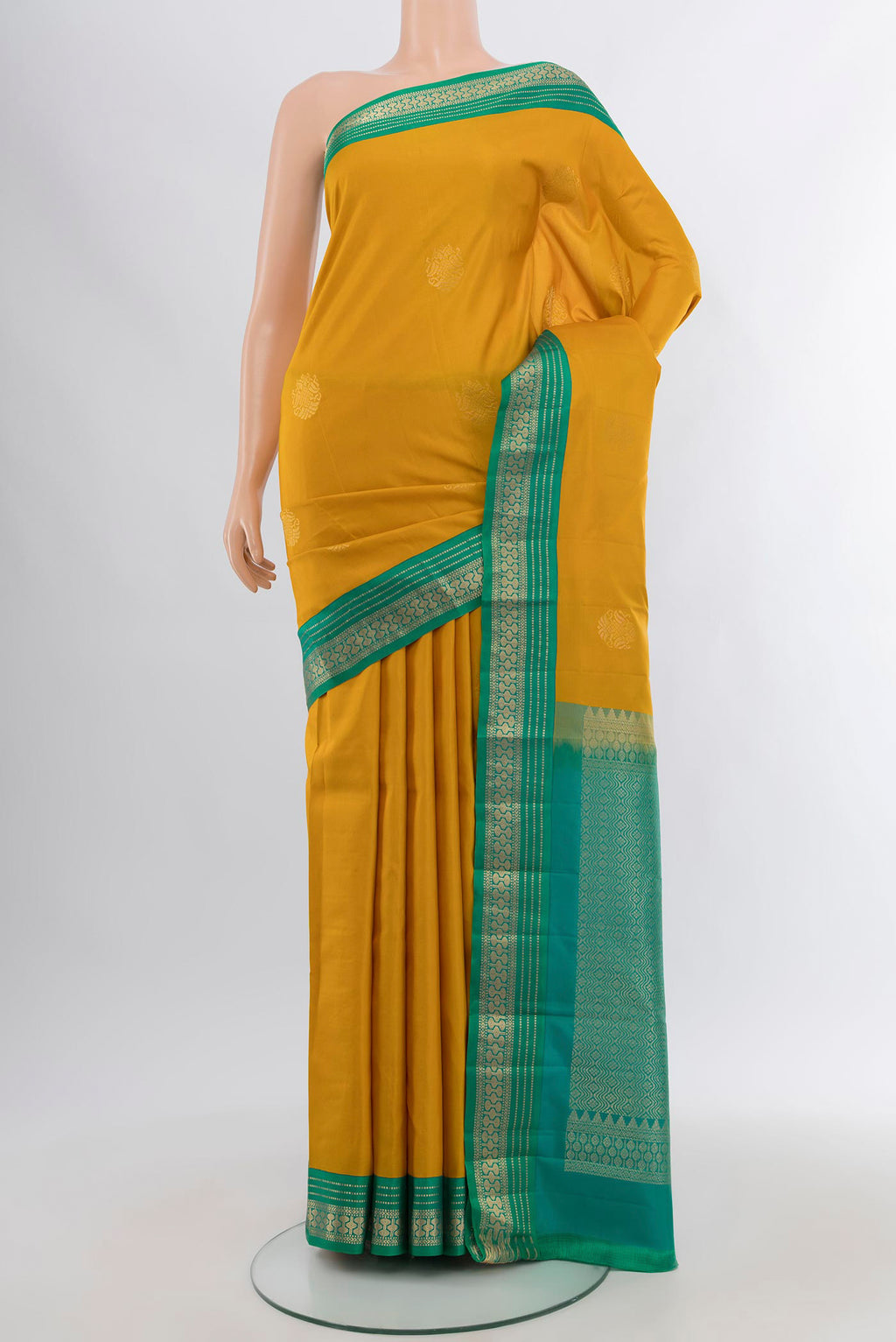 Mustard Kanchipuram Silk Saree with Zari Butta on the body and Zari Border.  displayed on a mannequin