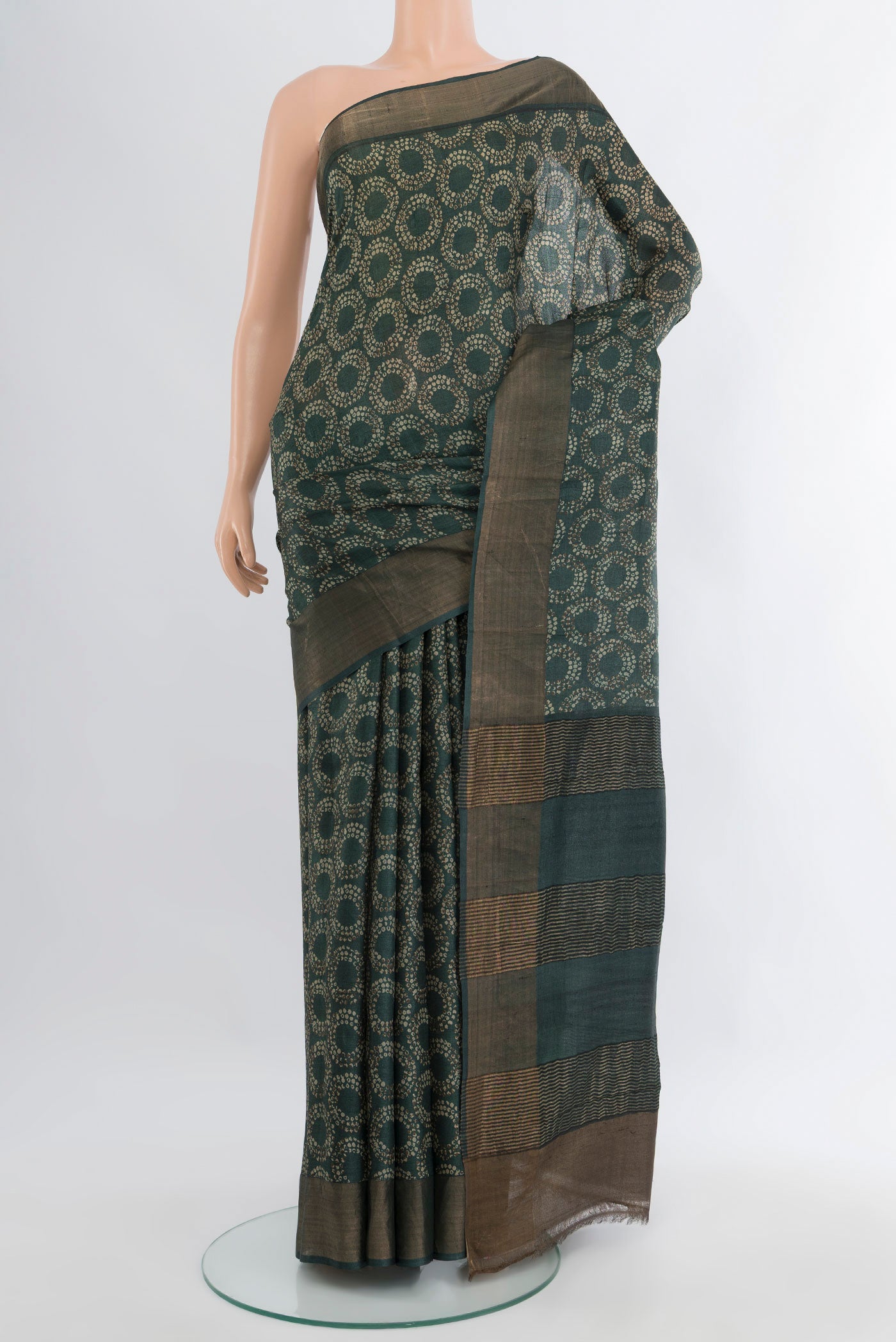 Bottle Green Tussar Silk Saree with Floral Print on the body and Zari Border.  displayed on a mannequin
