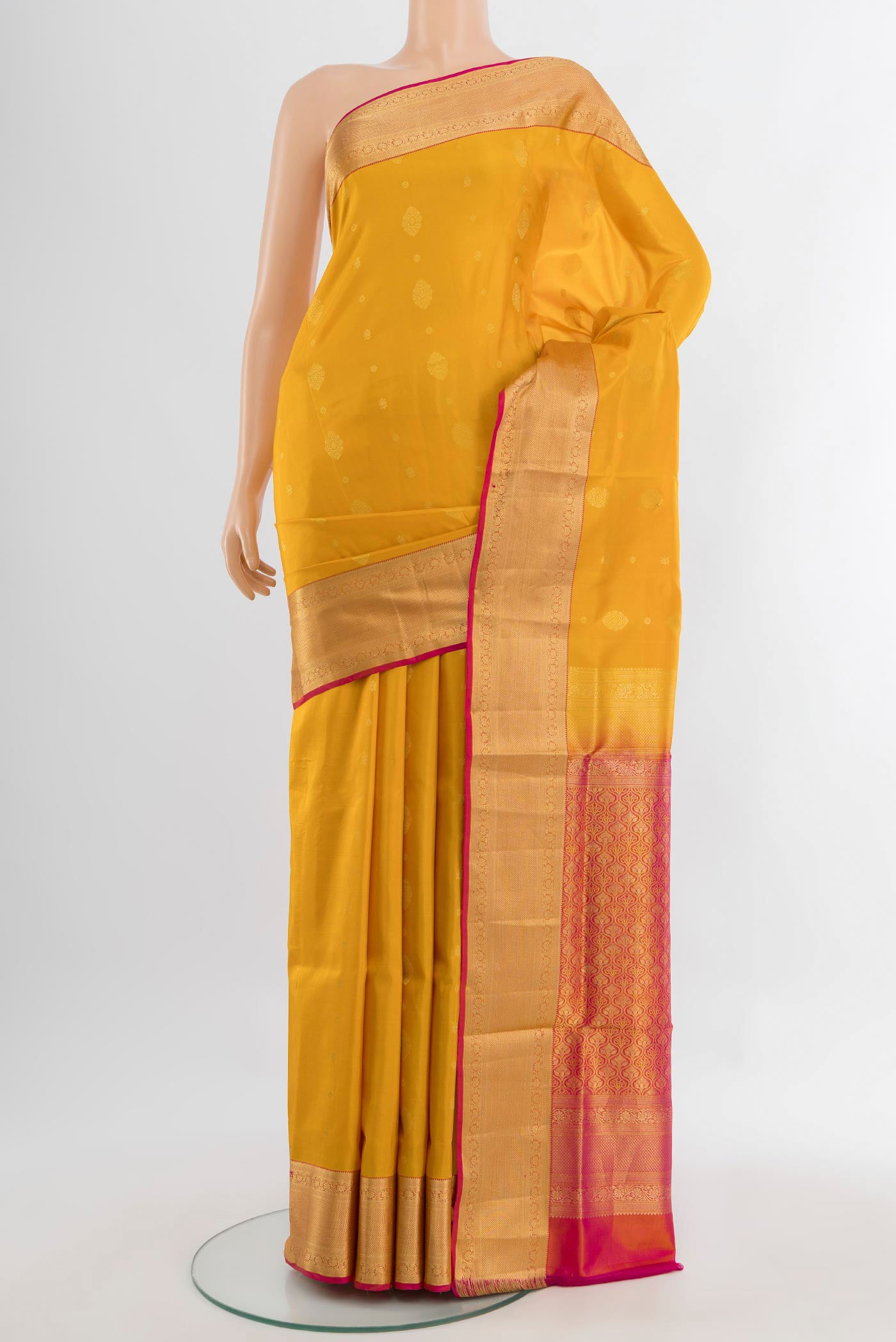 Mustard Soft Silk Saree with Zari Butta on the body and Silk Border.  displayed on a mannequin