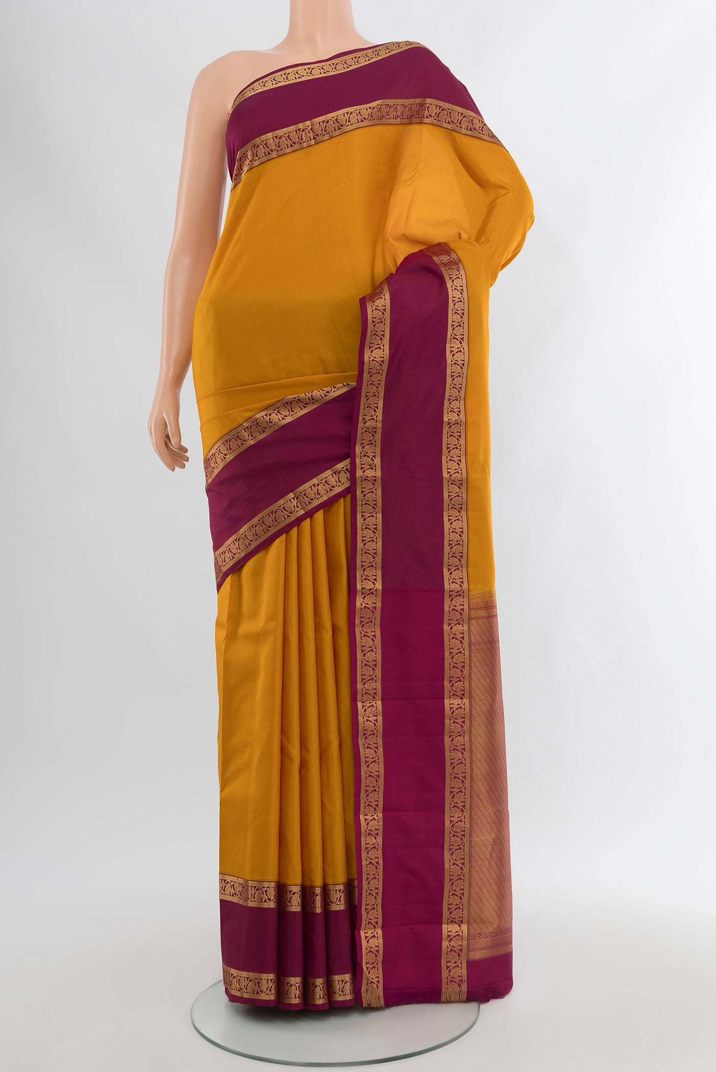 Mustard Kanchipuram Silk Saree with Zari Butta on the body and Silk Border.  displayed on a mannequin