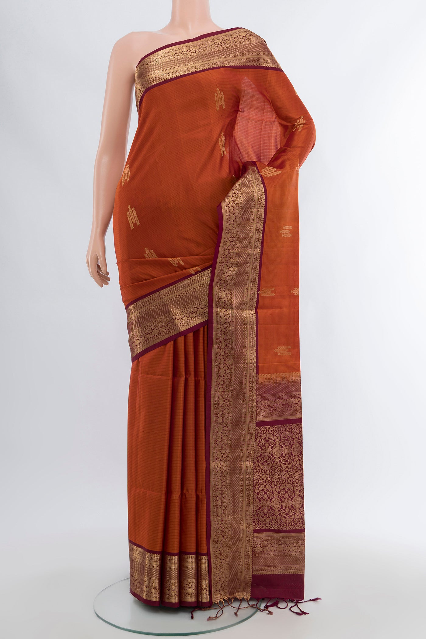 Rust Soft Silk Saree with Zari Butta on the body and Zari Border.  displayed on a mannequin