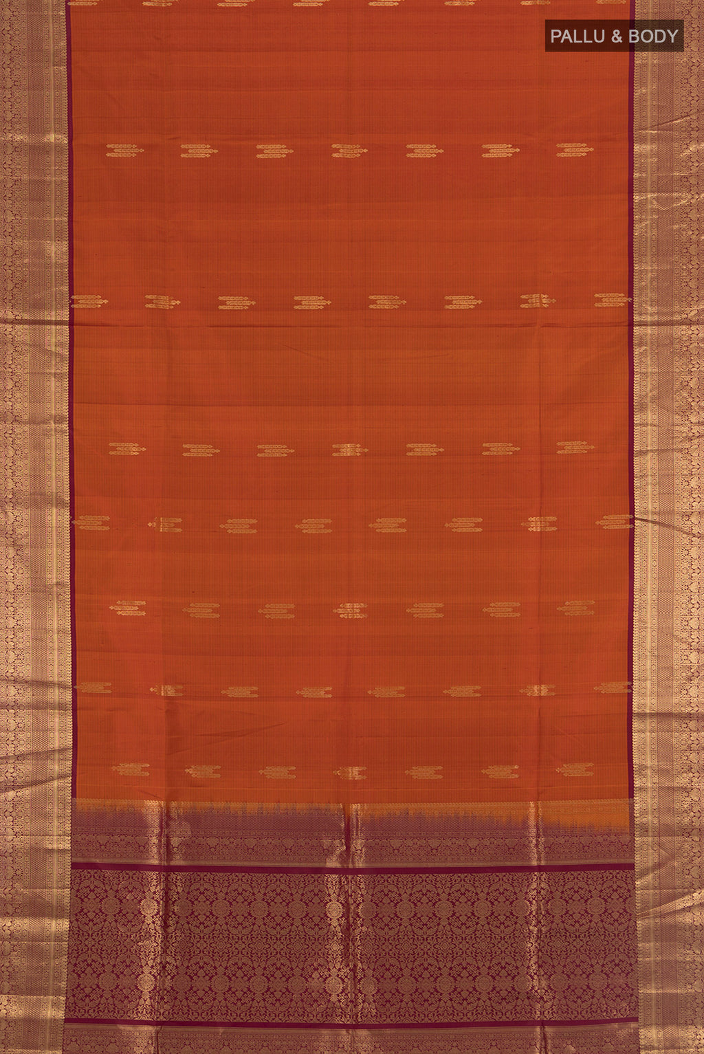 Flat view of Rust Soft Silk Saree with Zari Butta on the body and Zari Border. 