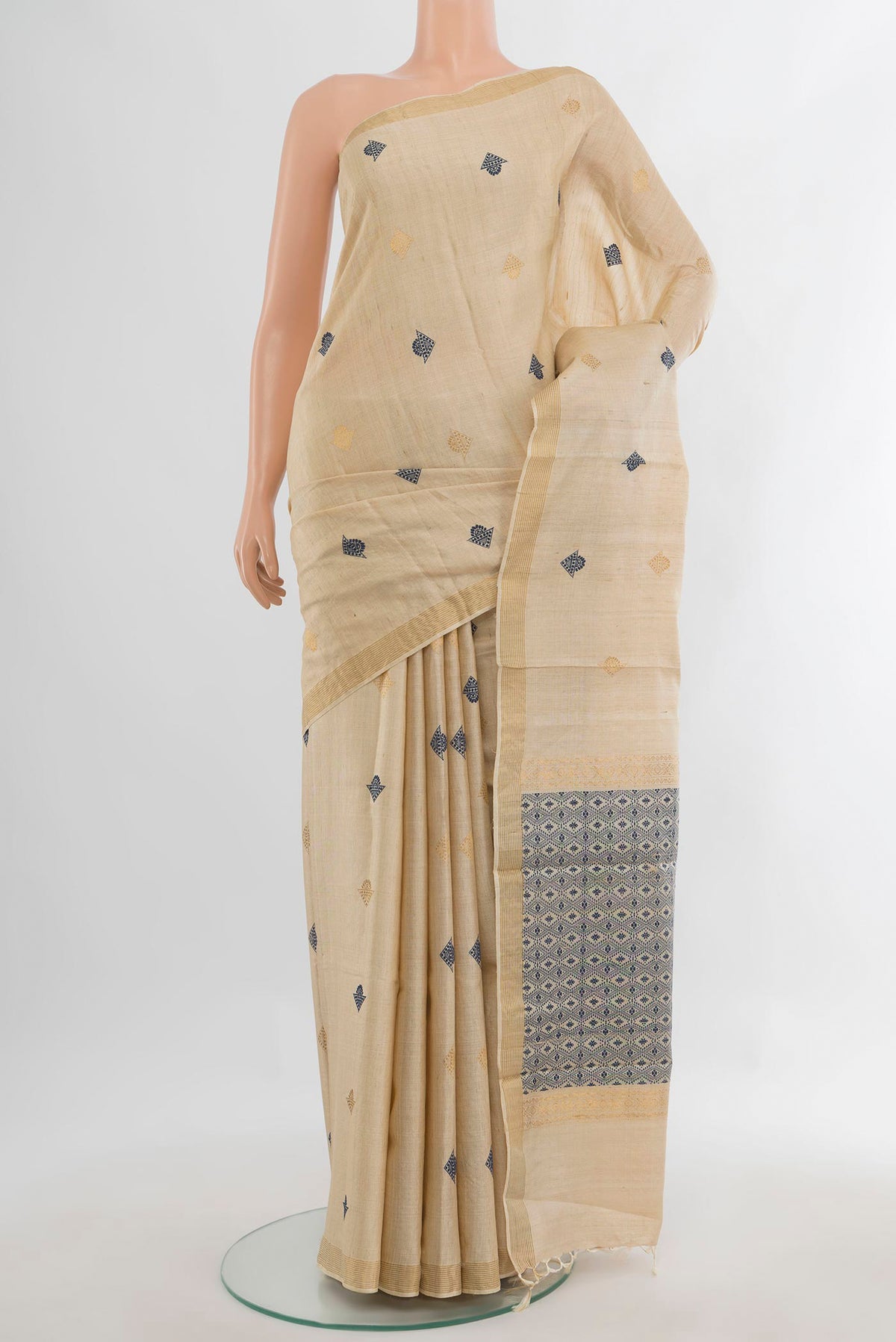 Cream Tussar Saree with Thread Butta on the body and Zari Border.  displayed on a mannequin